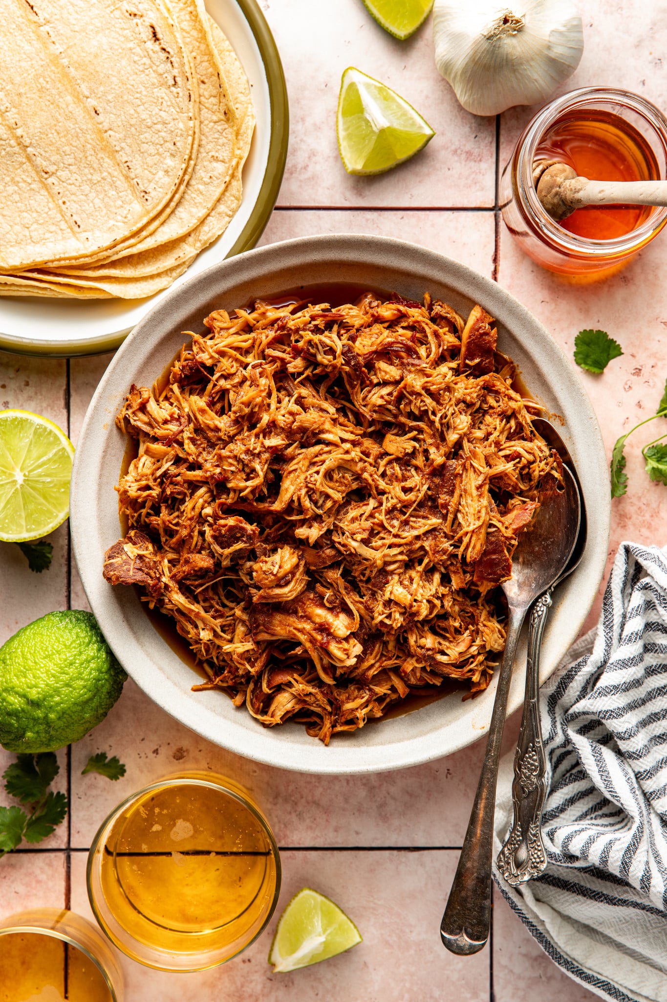 Slow cooker honey chipotle chicken in bowl with serving spoons on the side.
