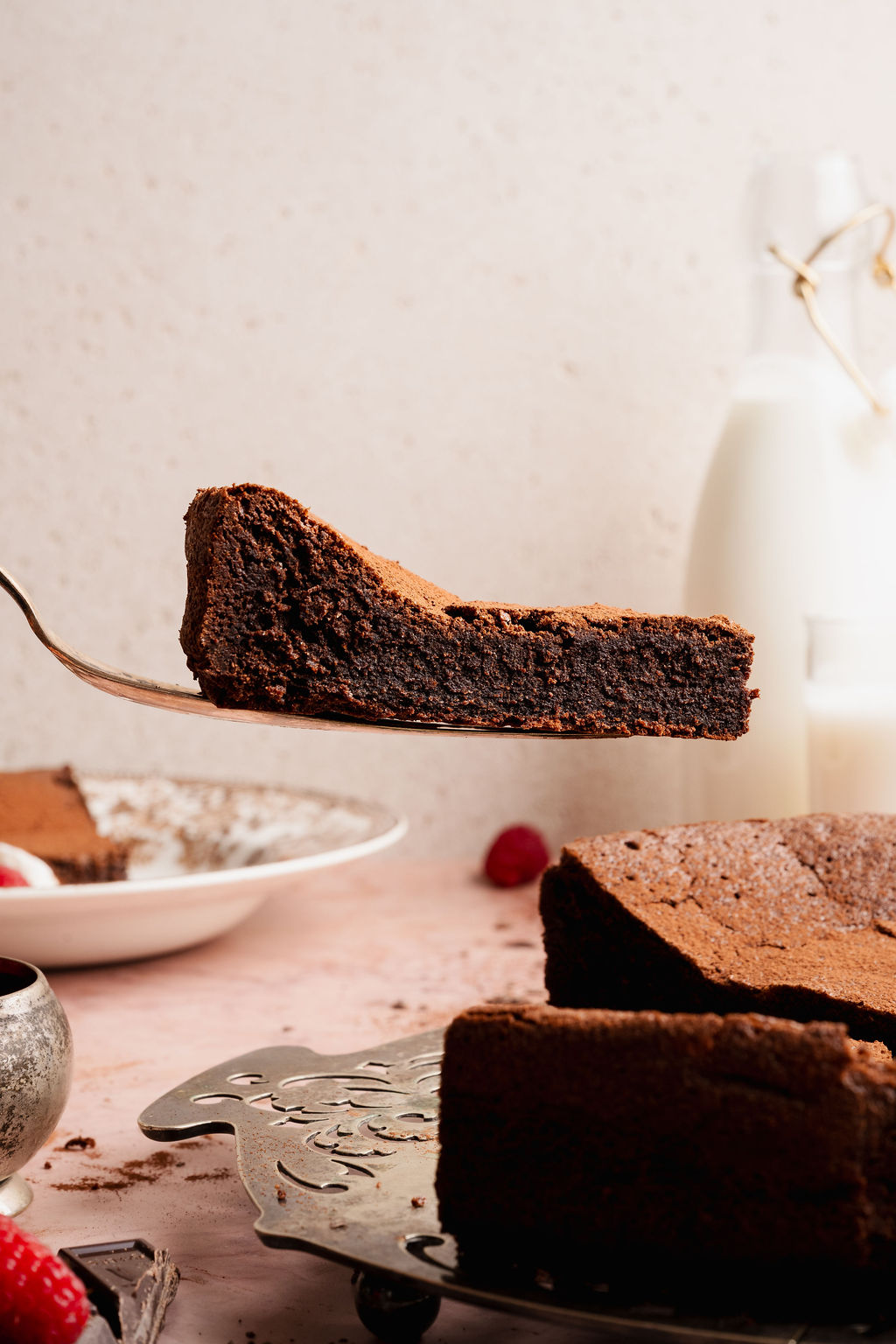 Side view of a single slice of flourless chocolate cake resting on a cake server, highlighting the rich, dark chocolate crumb and smooth texture.