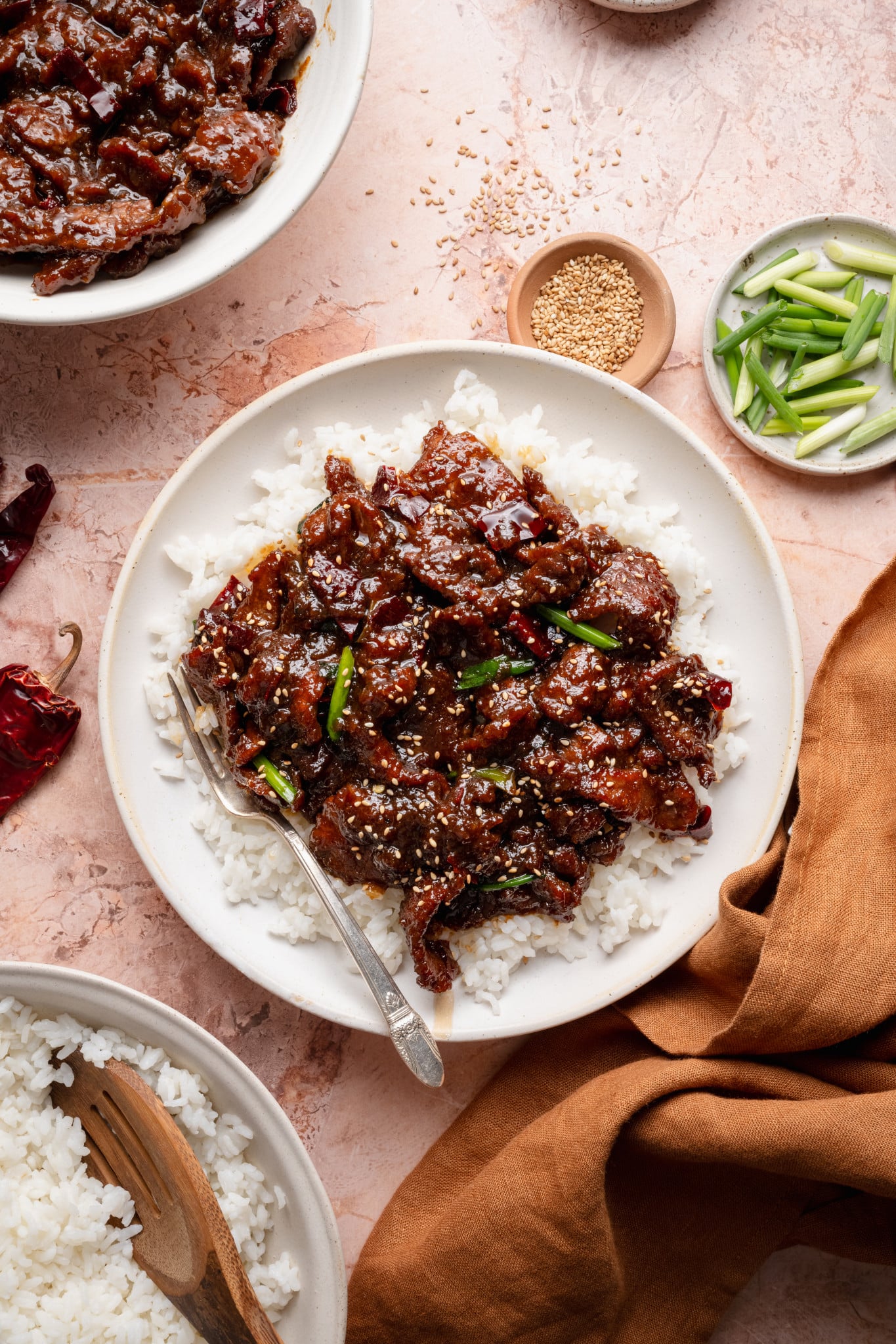 Mongolian beef served over rice on plate with fork on the side.