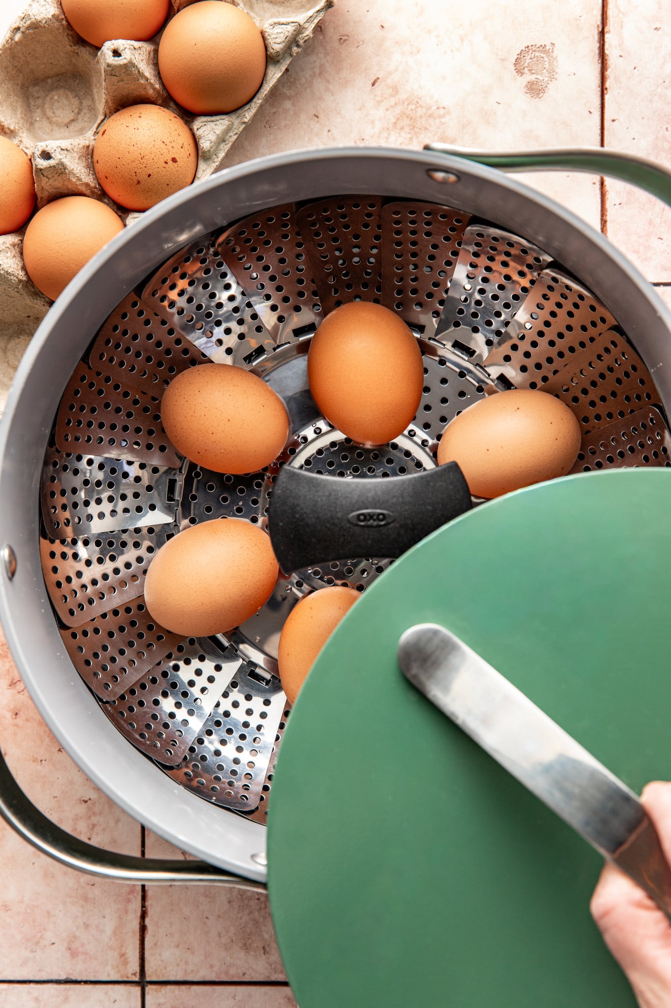 Eggs placed on a steamer in a large green pot.