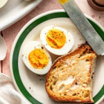 A steamed hard boiled egg cut in half and served on a plate with a piece of toast.