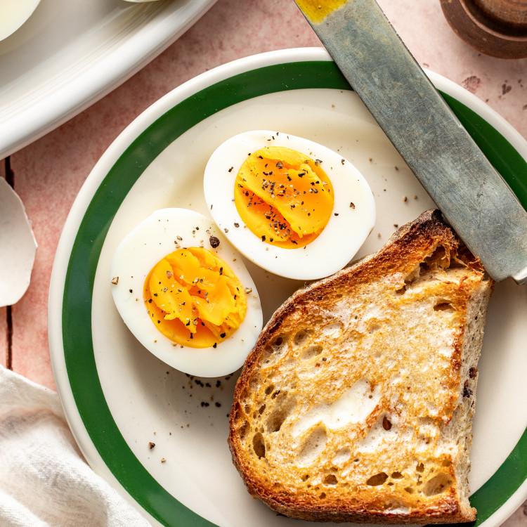 A steamed hard boiled egg cut in half and served on a plate with a piece of toast.
