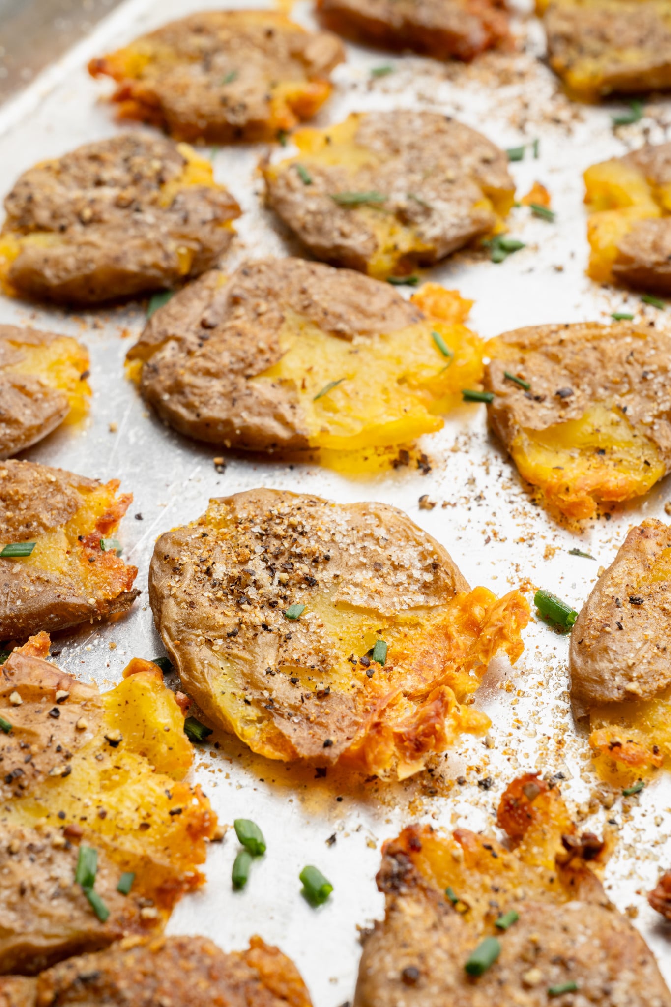Upclose shot of crispy smashed potatoes on baking sheet.