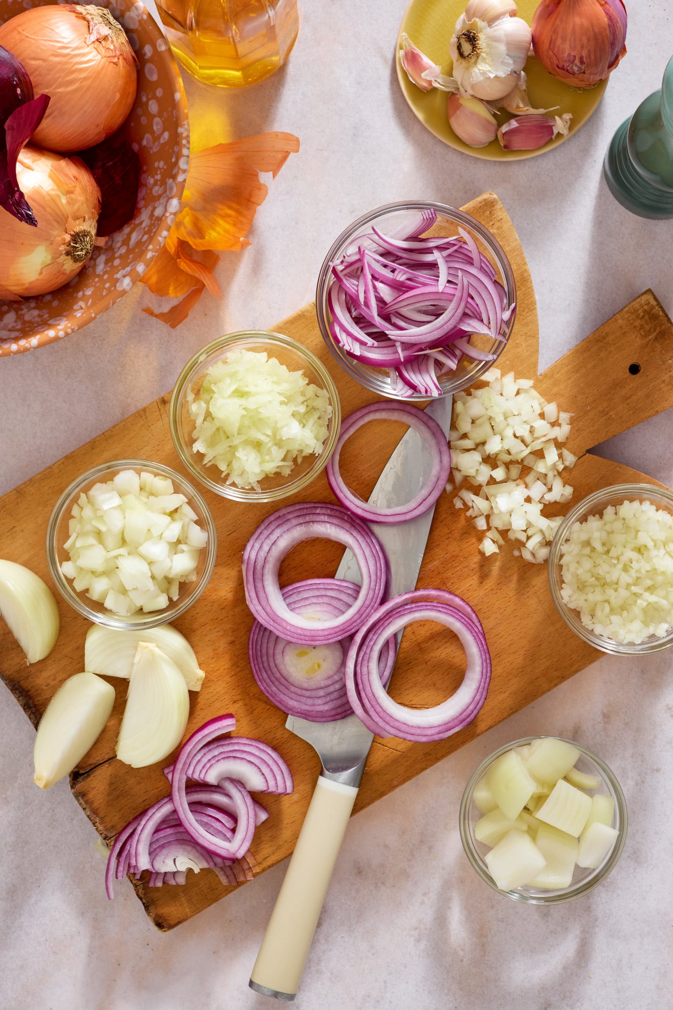 All the different variations of how to cut on onion displayed on a cutting board.