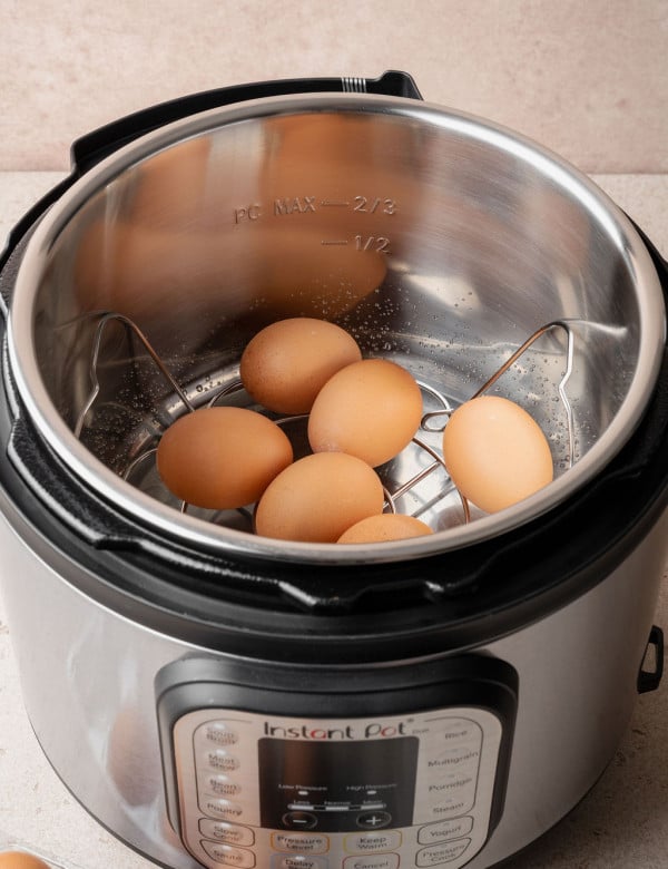 Large eggs resting on the trivet inside an Instant Pot insert before pressure cooking hard boiled eggs.