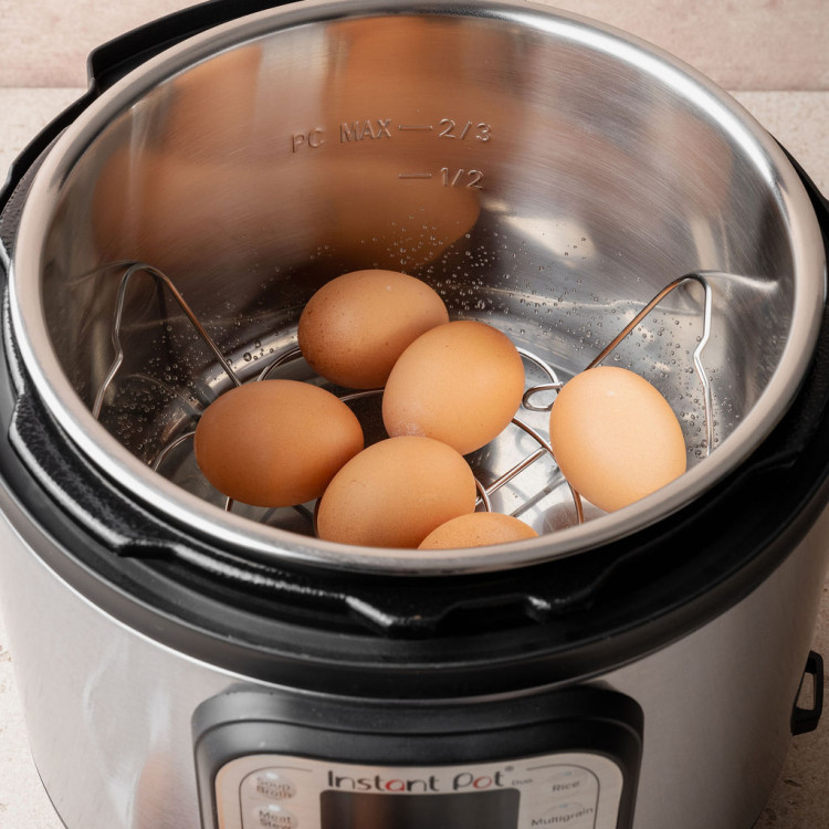 Large eggs resting on the trivet inside an Instant Pot insert before pressure cooking hard boiled eggs.