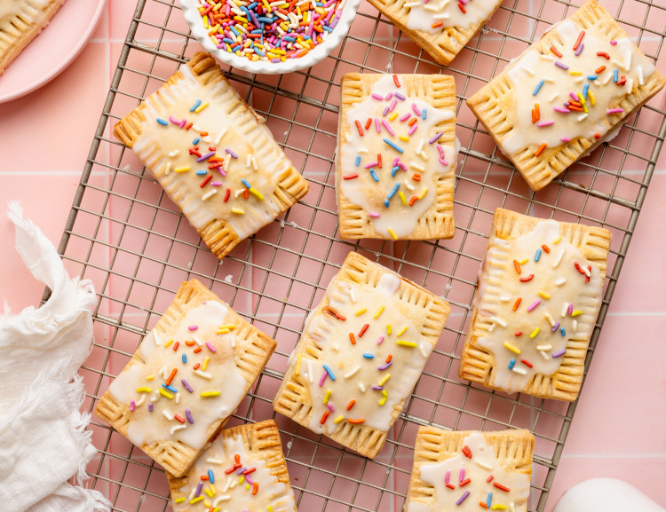 Nine strawberry pop tarts setting on a wire rack.