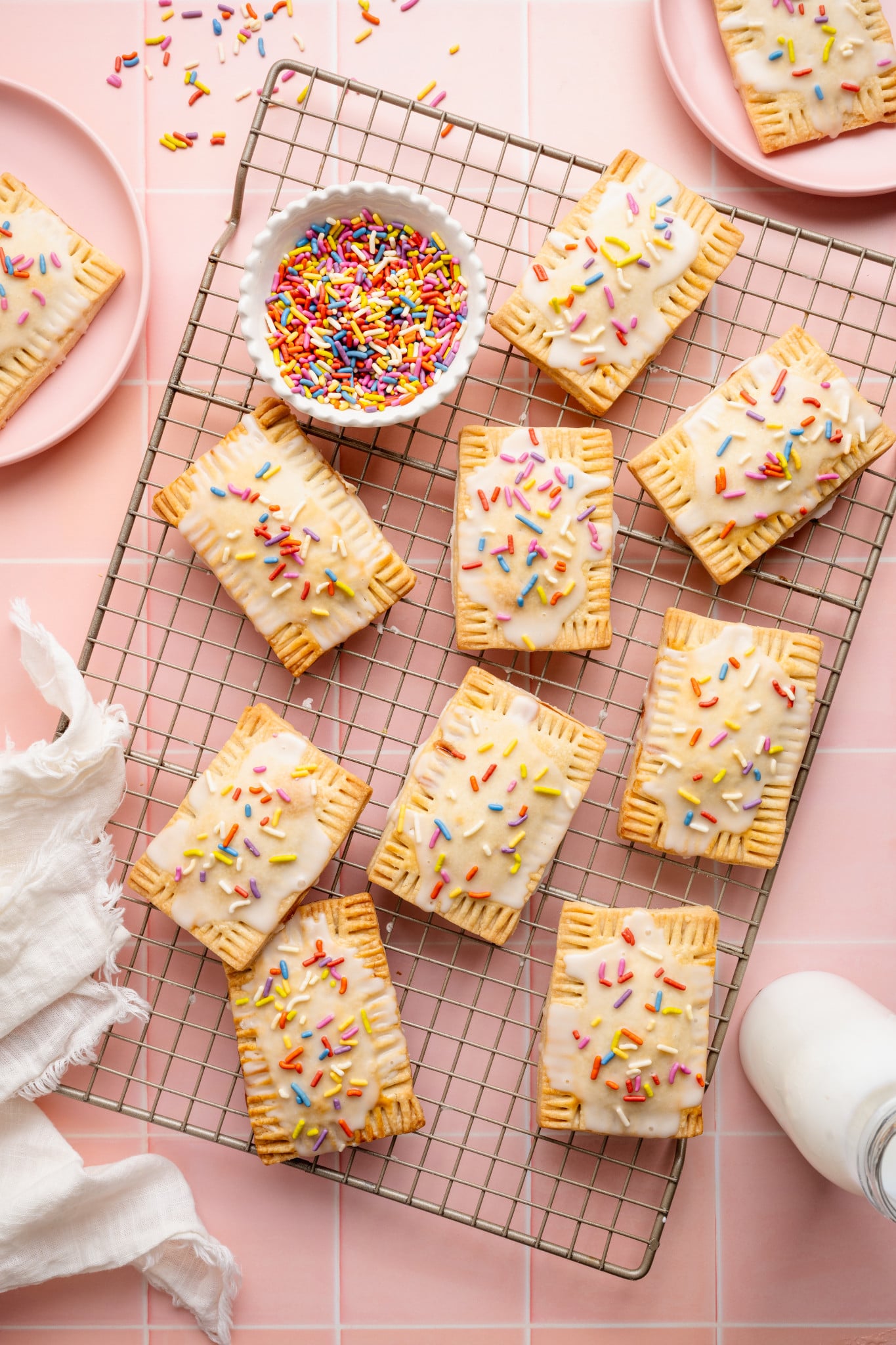 Nine strawberry pop tarts setting on a wire rack.