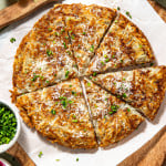 Potato pancake cut into slices and garnished with fresh herbs and parmesan cheese.