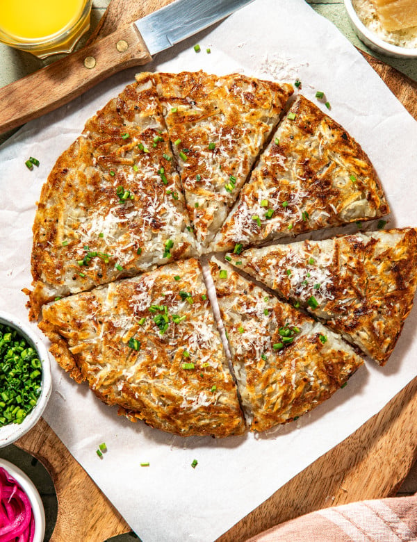 Potato pancake cut into slices and garnished with fresh herbs and parmesan cheese.