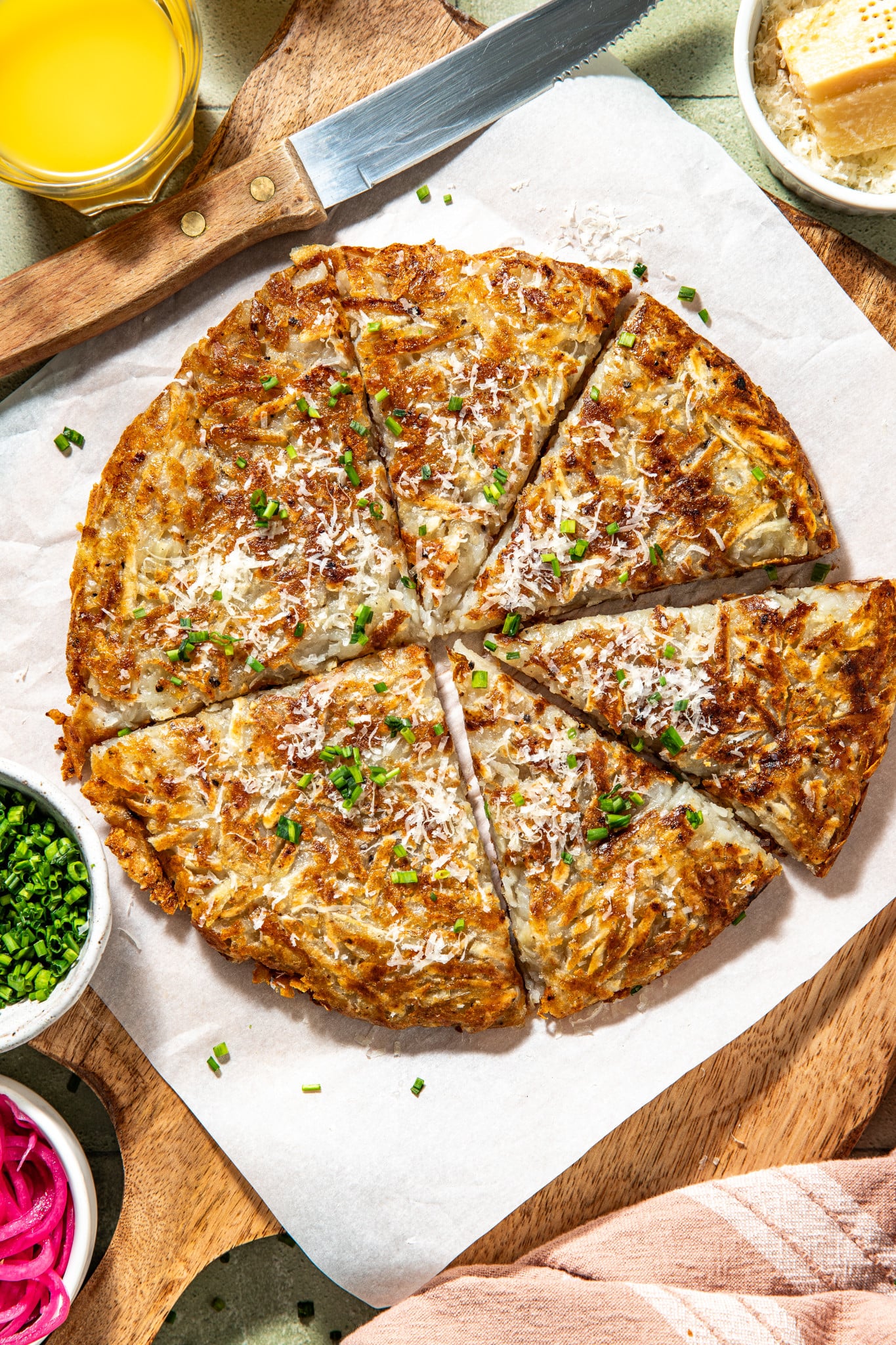Potato pancake cut into slices and garnished with fresh herbs and parmesan cheese.