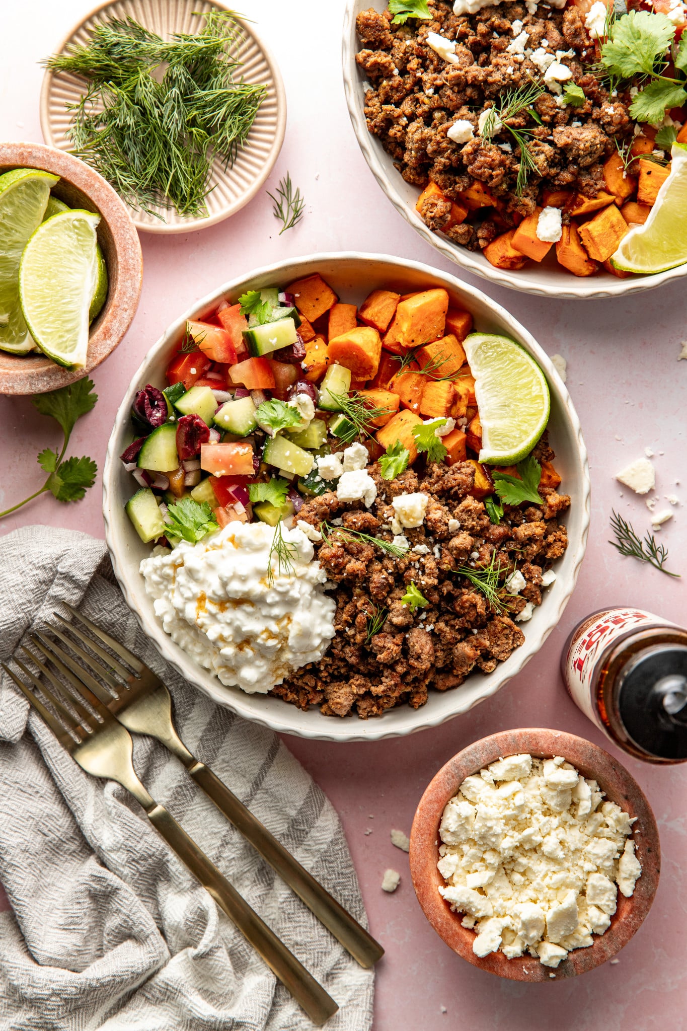Mediterranean ground beef sweet potato bowls served in large bowl and garnished with fresh herbs and lime wedge.