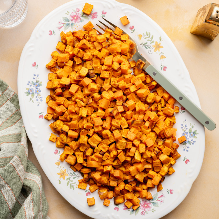 Cooked sweet potatoes on a large oval serving plate with fork on the right side.