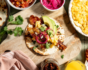 Adding toppings to the assembled breakfast taco.