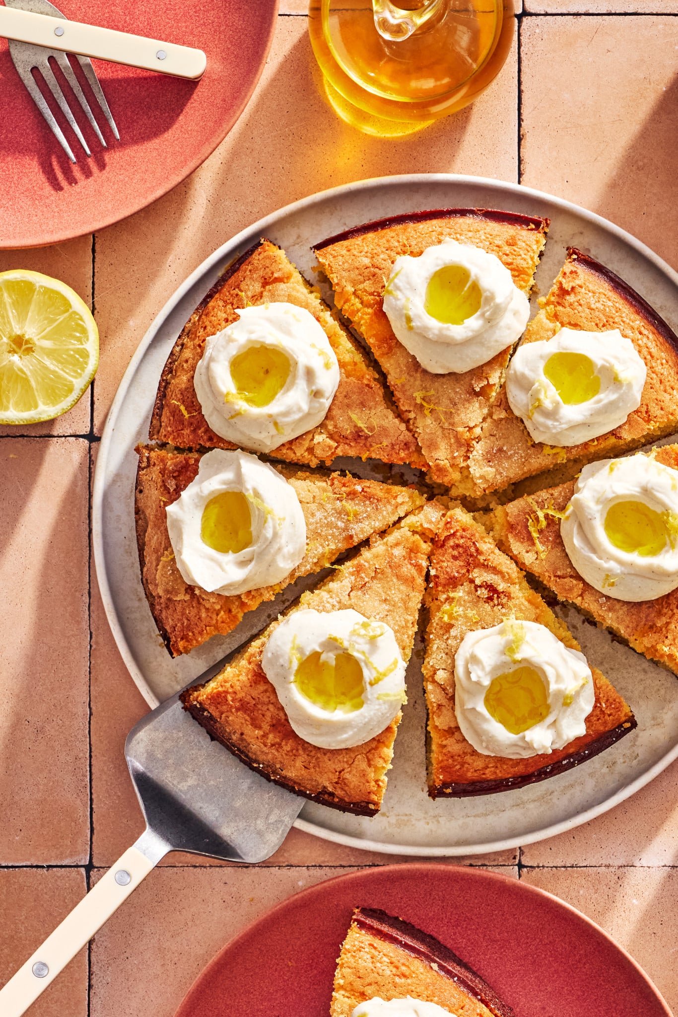 Lemon olive oil ricotta cake sliced and topped with dollops of whipped ricotta topping, olive oil and lemon zest.