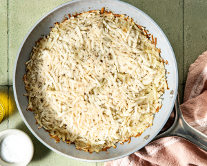 Shredded potatoes pressed down into 10-inch non-stick skillet.