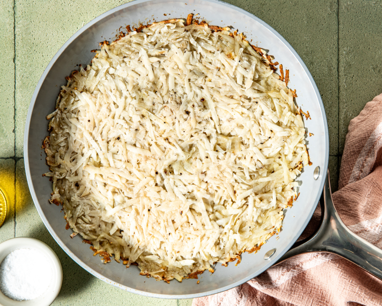 Shredded potatoes pressed down into 10-inch non-stick skillet.