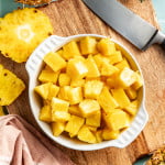 Fresh pineapple chunks cut and placed into large white bowl.