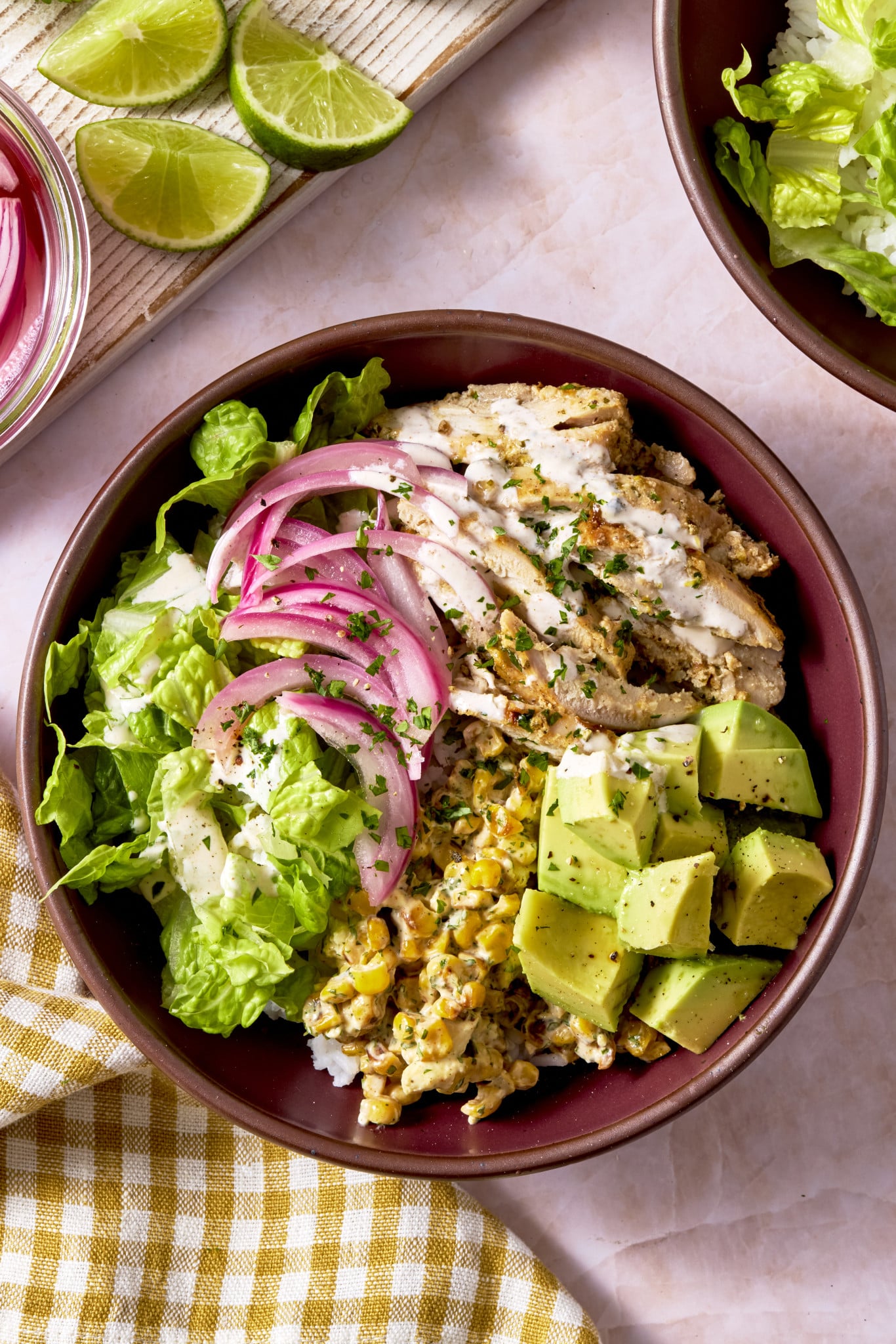 Street corn chicken bowl topped with avocado, lettuce and pickled onions.
