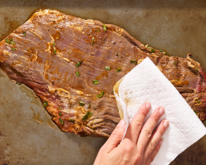 Patting carne asada dry before grilling.