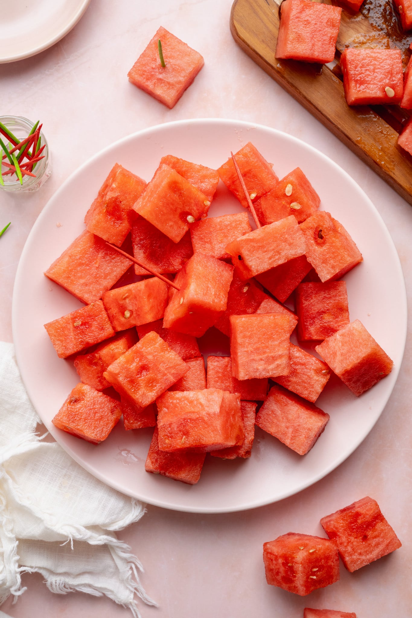 Watermelon cubes placed on a plate with toothpicks in a couple of the pieces.
