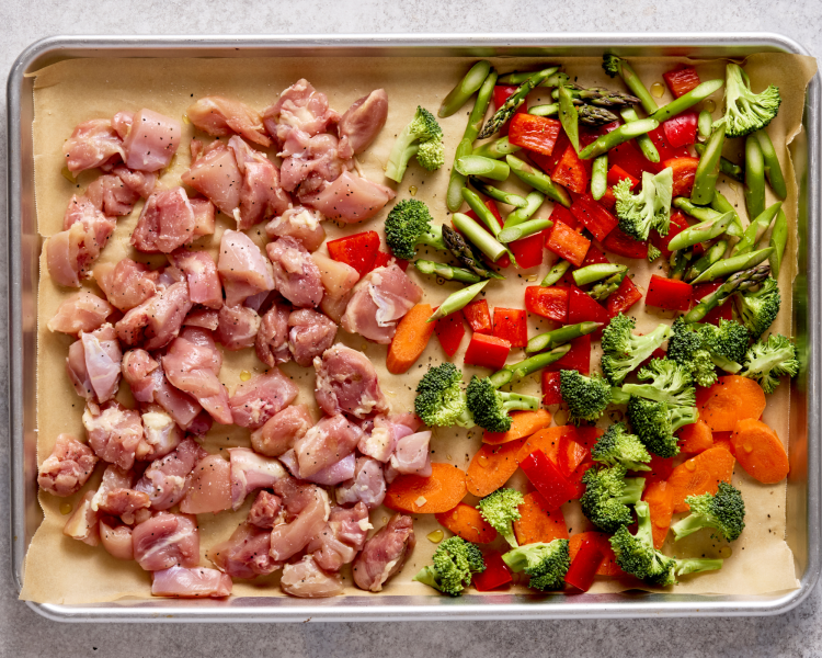 Chicken and veggies placed on sheet pan and tossed with olive oil and salt and pepper.