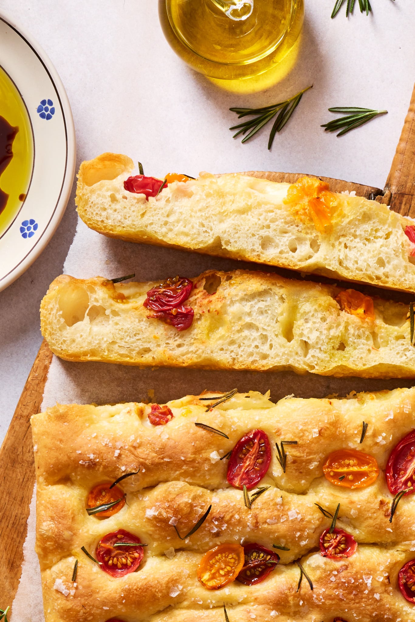 Homemade tomato rosemary focaccia sliced open to reveal a soft, airy crumb with large air pockets and a golden crust.