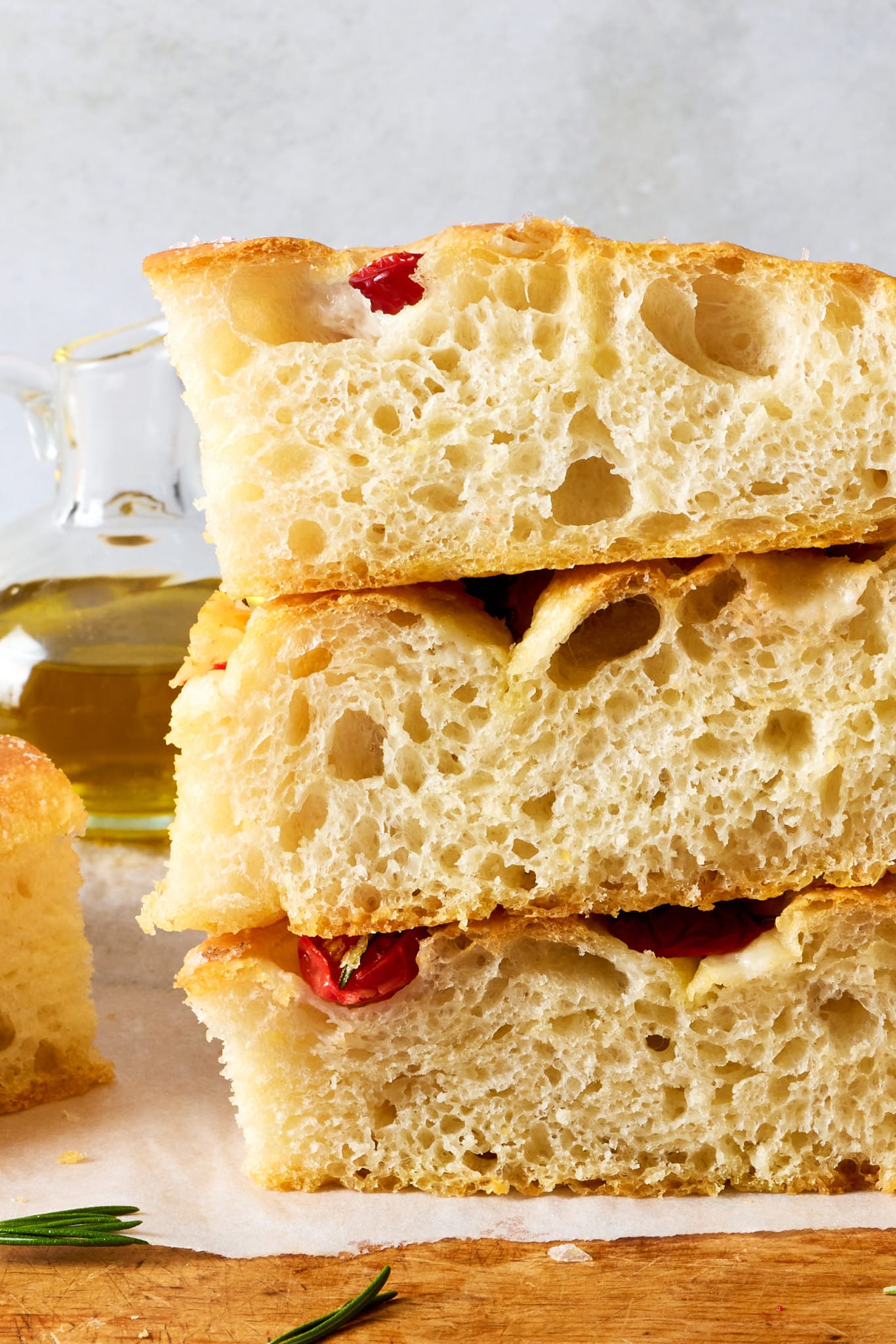 Stacked slices of homemade focaccia showcasing an airy, open crumb with large air pockets and a crisp golden crust.