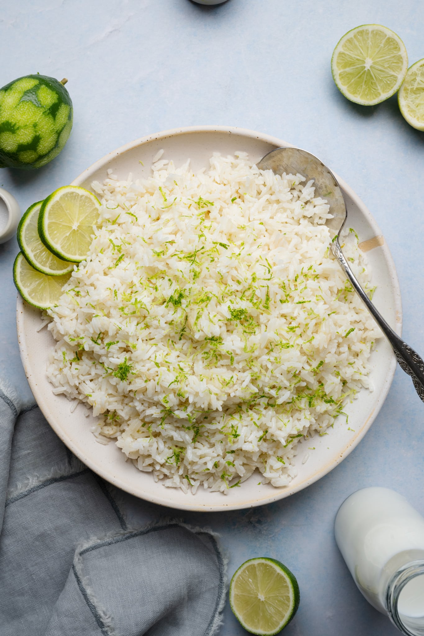 Coconut lime rice served on a plate garnished with fresh lime zest and serving spoon on the side.