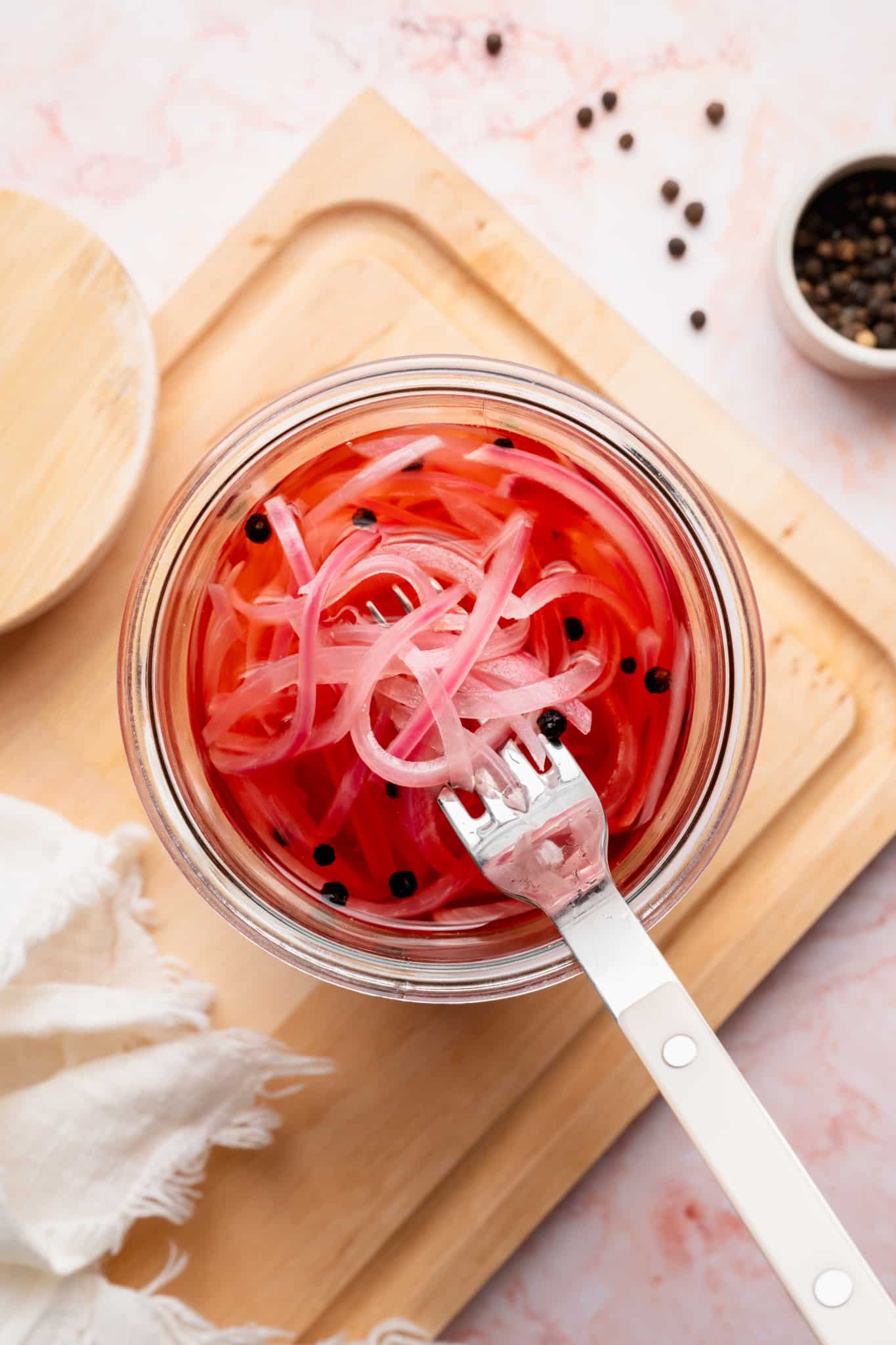 Fork lifting pickled onions out of jar.