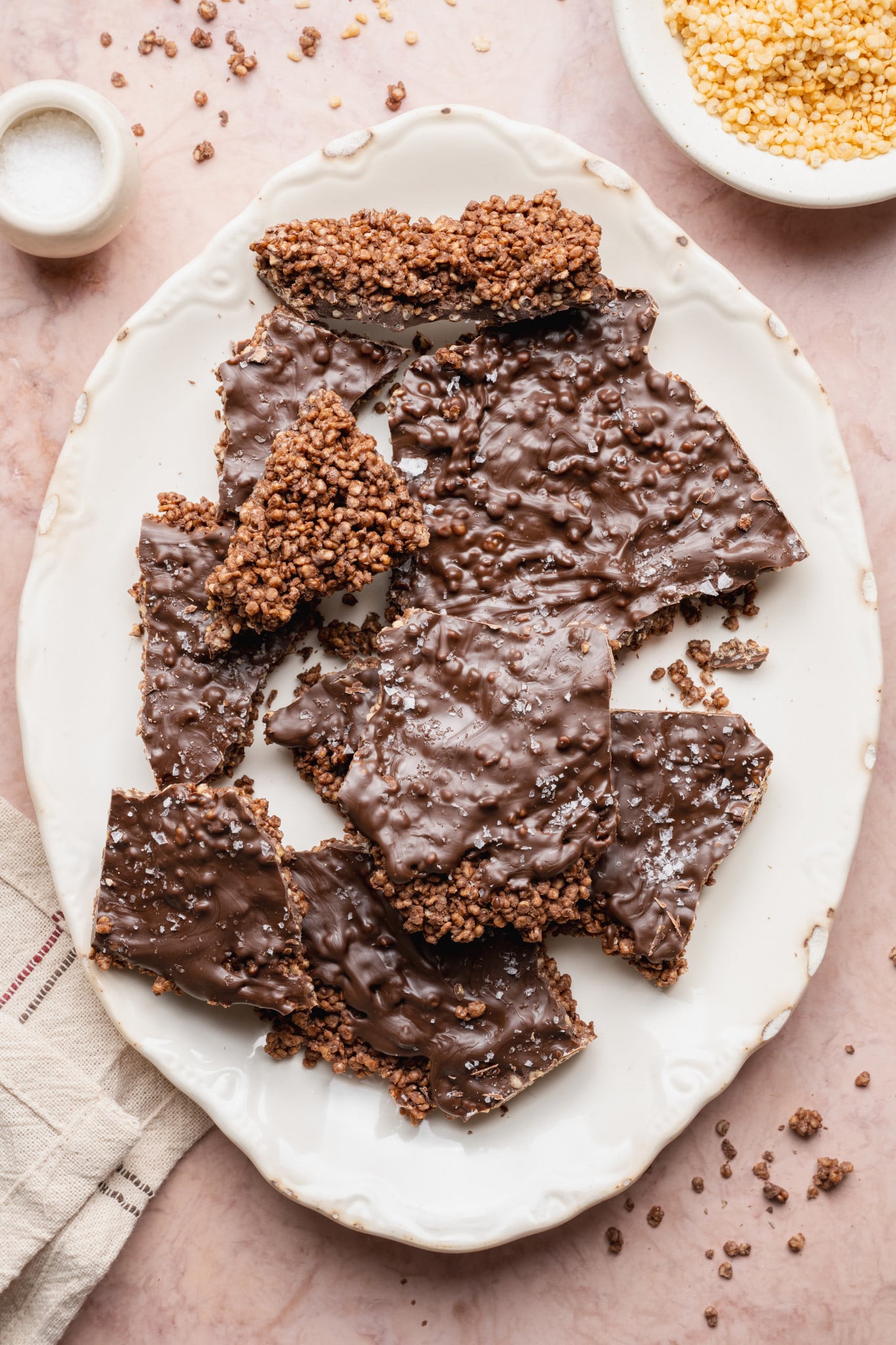 Pieces of chocolate covered quinoa bark on white oval serving platter.