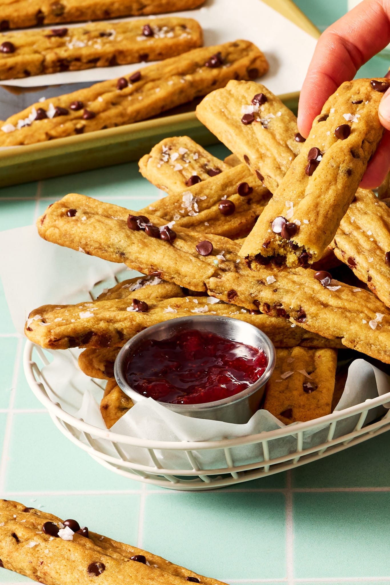 Hand holding half a cookie fry being dip in strawberry syrup.