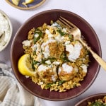 Mediterranean meatball and orzo in bowl topped with tzatziki and lemon wedge.