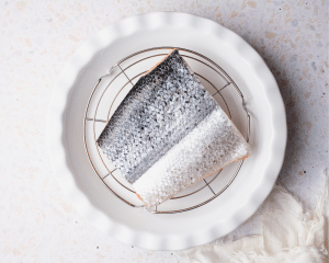 Placing salmon on cooling wrap above plate.